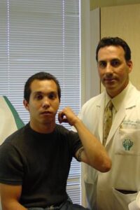 AC is a 25 year old male who was assaulted with a baseball bat. He sustained a shattered proximal ulna fracture with elbow dislocation. Surgery required application of a plate and screws, as well as pinning and cerclage wiring. He worked diligently in therapy to regain the excellent range of motion in his elbow as demonstrated in the photo with me.